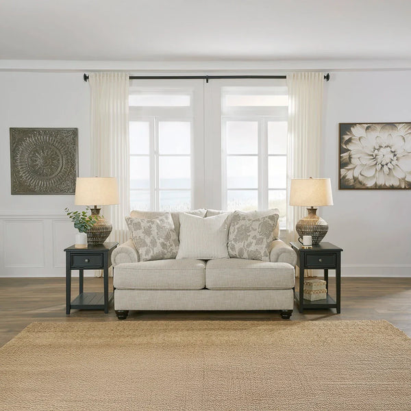 Light-hued loveseat with richly textured fabric and roll arms.